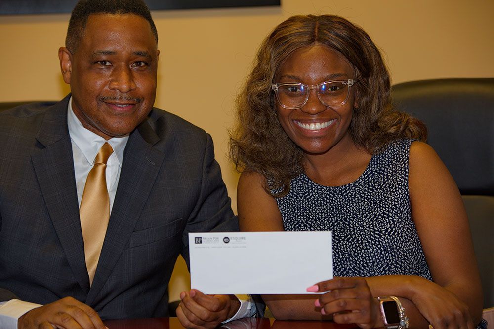 A man and a woman are sitting at a table holding an envelope