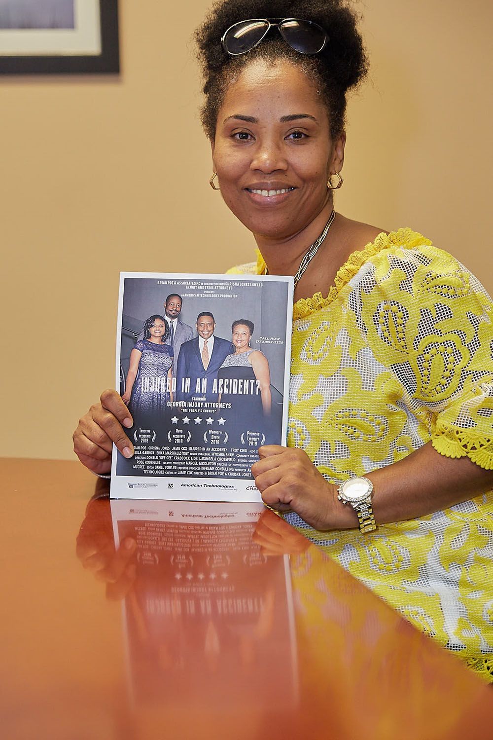 A cheerful woman is sitting at a table holding a flyer