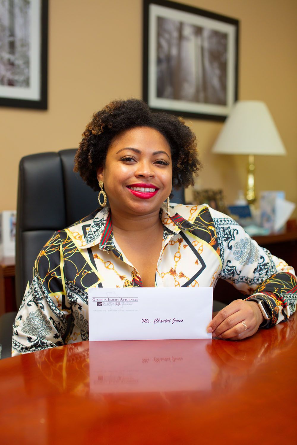 A joyful woman is sitting at a desk holding a check