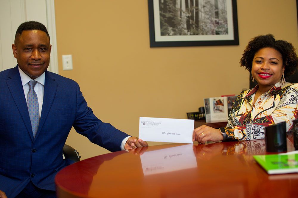 Brian D. Poe, Esq. handing a check to a joyful client