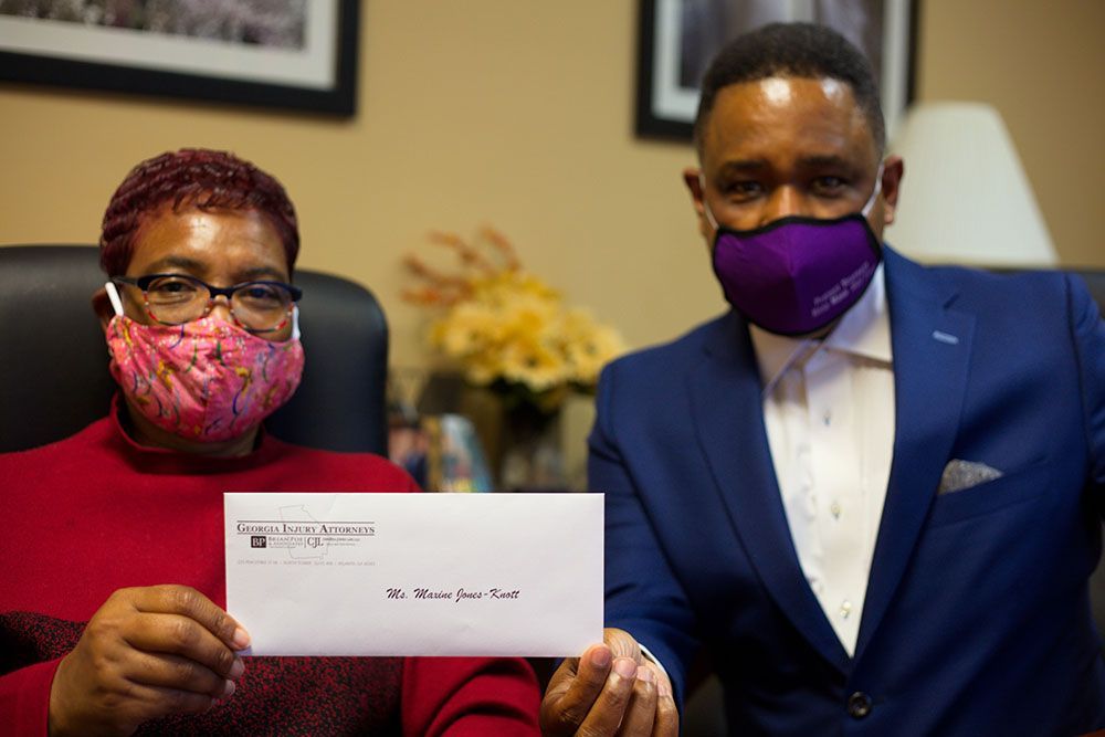 A man and a woman wearing masks are holding an envelope