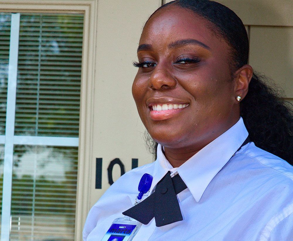 A woman wearing a white shirt and a black bow tie is smiling