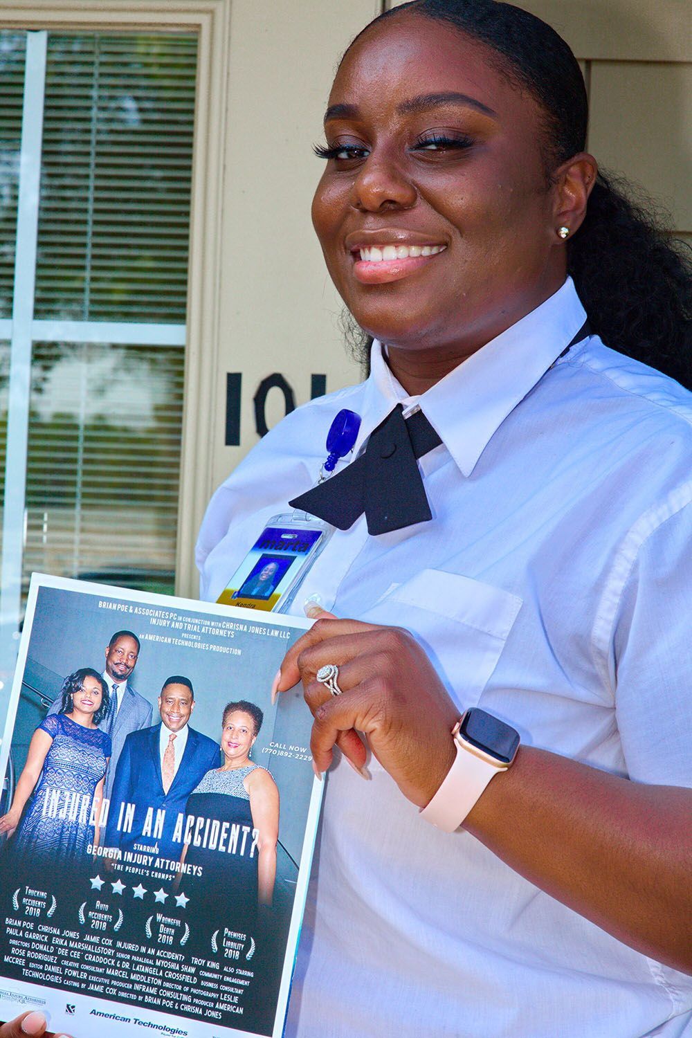 A woman in a white shirt and tie is holding a Georgia Injury Attorneys flyer
