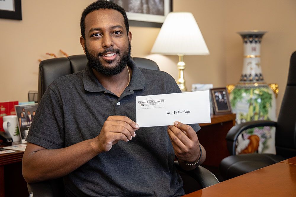 A man is sitting at a desk holding an envelope