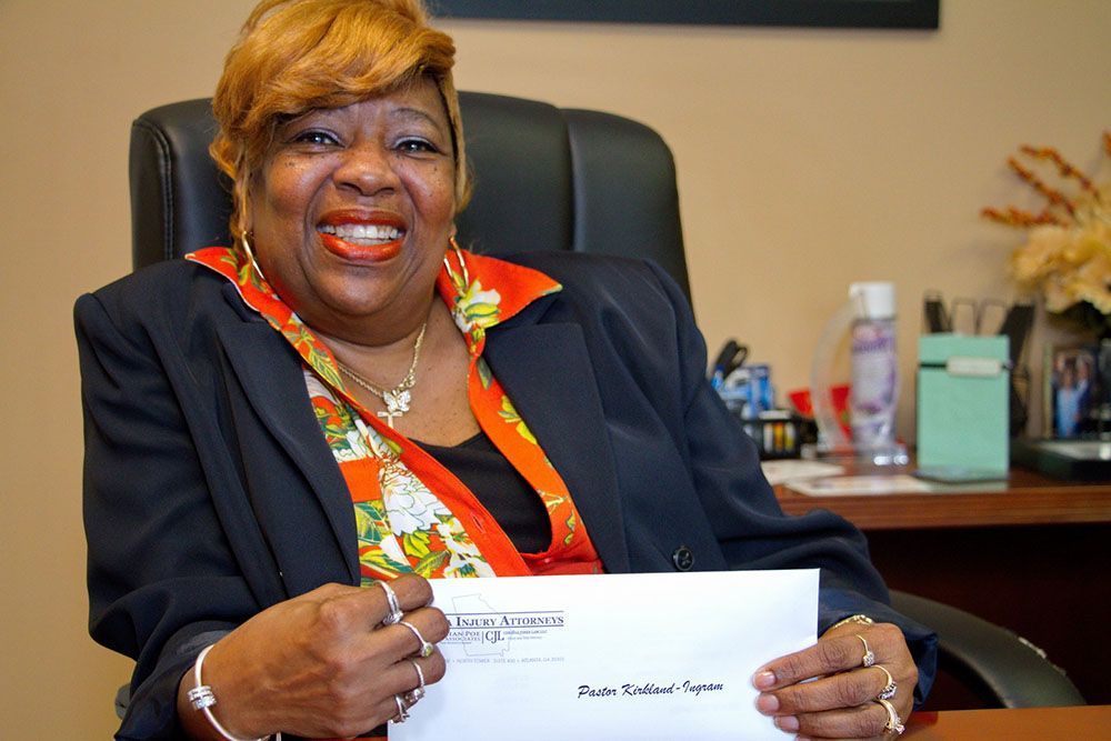 A joyful female client is sitting in a chair holding a check