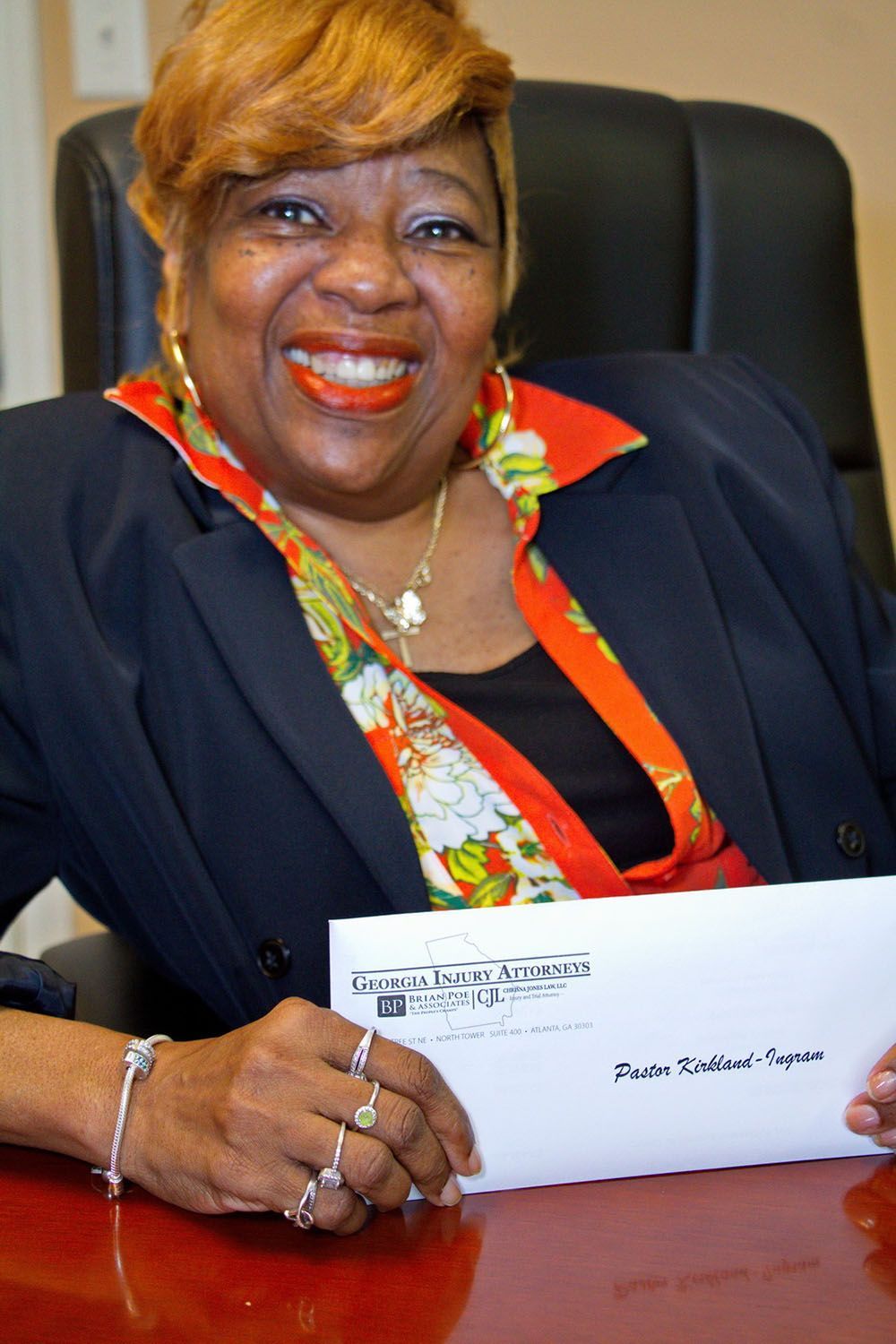 A client is smiling while sitting at a desk holding a check