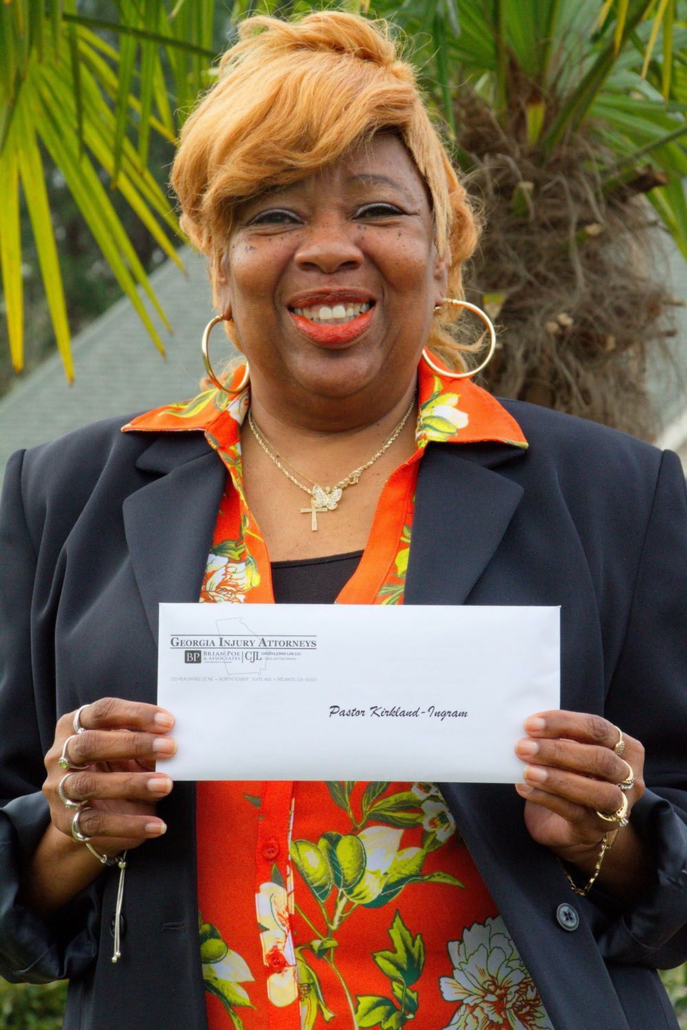 A woman is holding a check in front of a palm tree