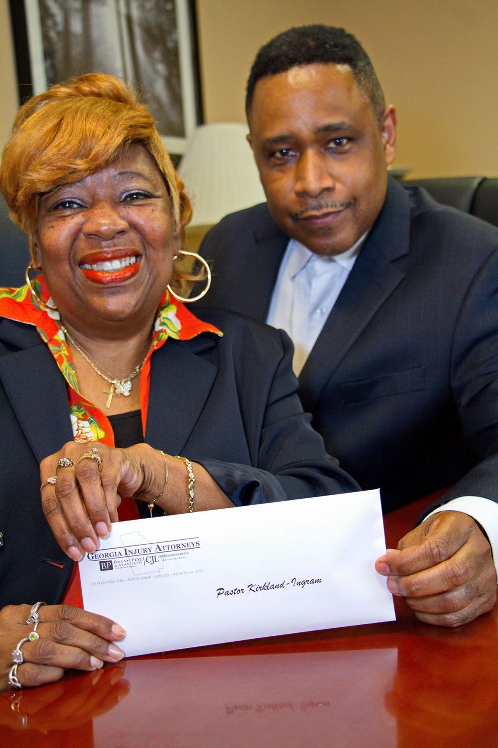 Brian D. Poe, Esq. and a cheerful woman are sitting at a table holding a check