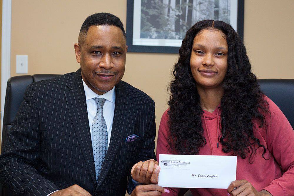 A man in a suit and tie is sitting next to a woman holding a check