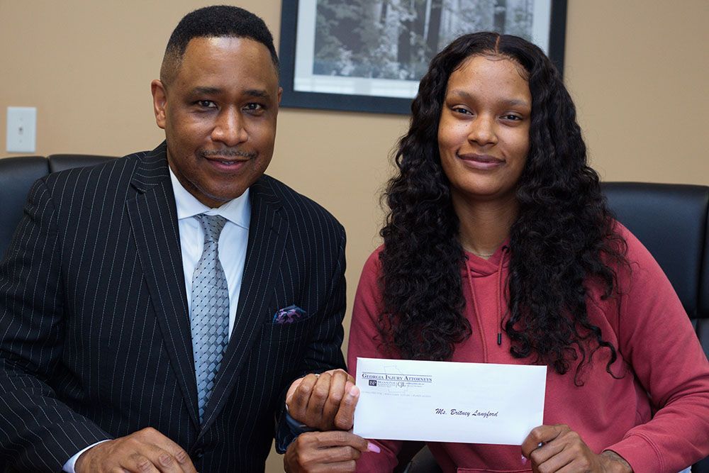 Brian D. Poe, Esq. is sitting next to a woman holding a check