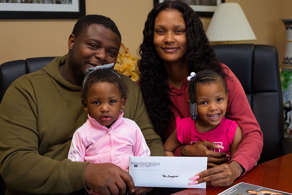 A family is sitting at a table holding an envelope