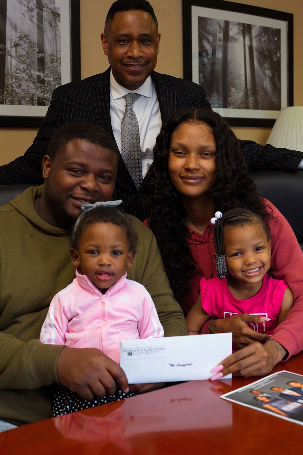 Brian D. Poe, Esq. and a happy family holding a check