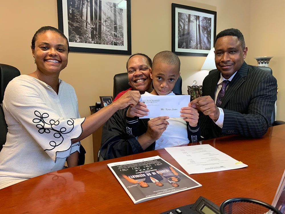 Georgia Injury Attorneys giving a check to a happy mother and child