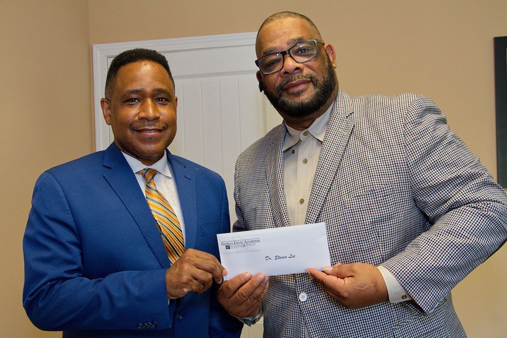 Two men in suits and ties are holding a check