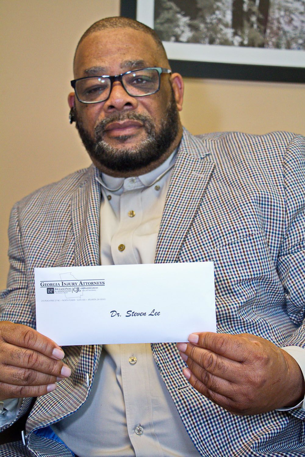 A man in a suit and glasses is holding a check in his hands