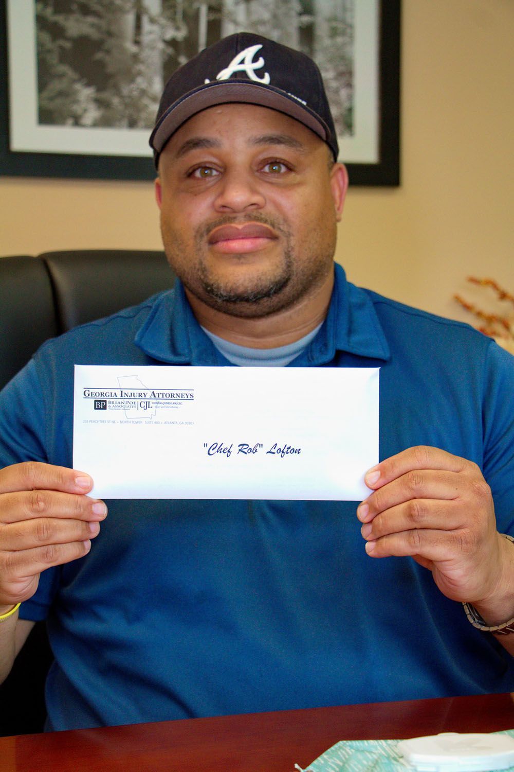 A man wearing a hat is holding a check