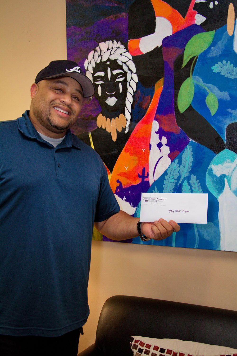 A man is holding a check in front of a painting