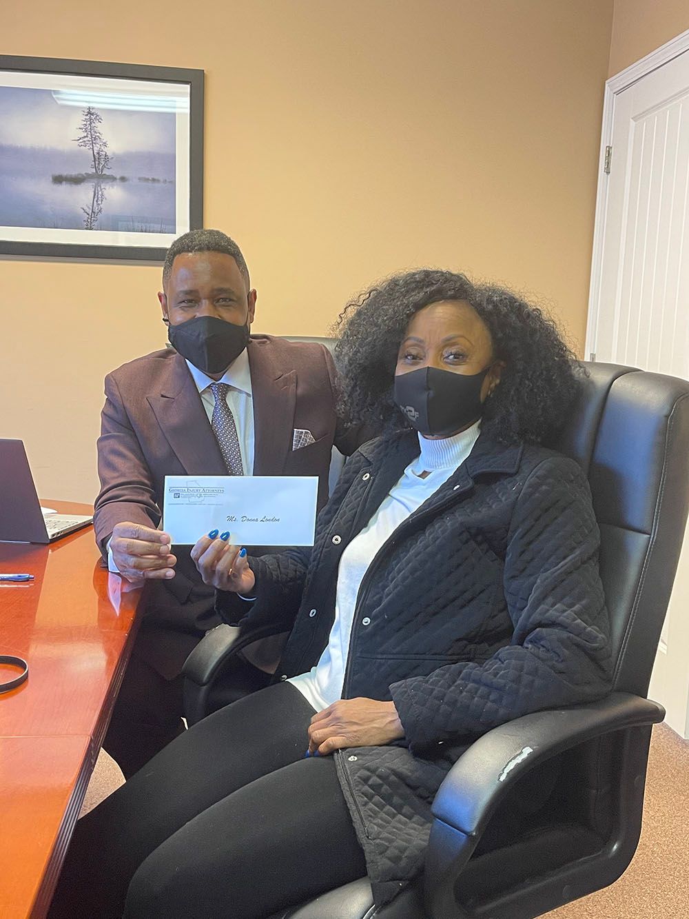 A man and a woman wearing masks are sitting at a table holding a check