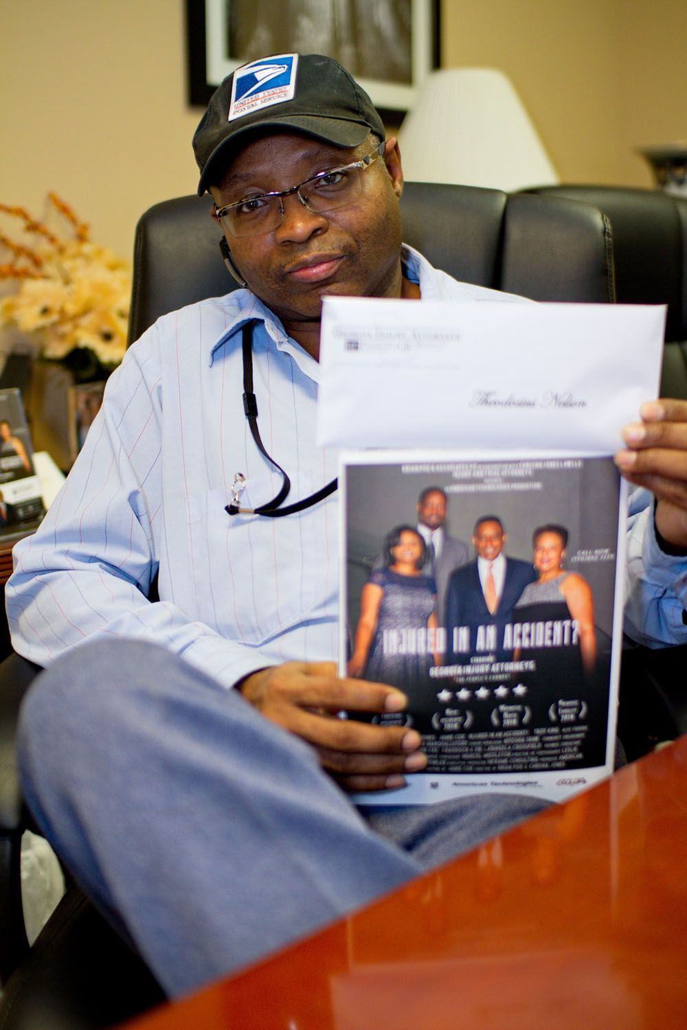 A man is sitting in a chair holding a flyer