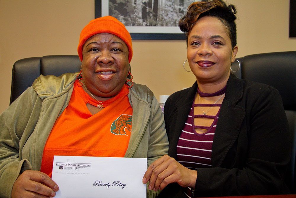 Jamie S. Cox, Esq. handing a check to a cheerful client