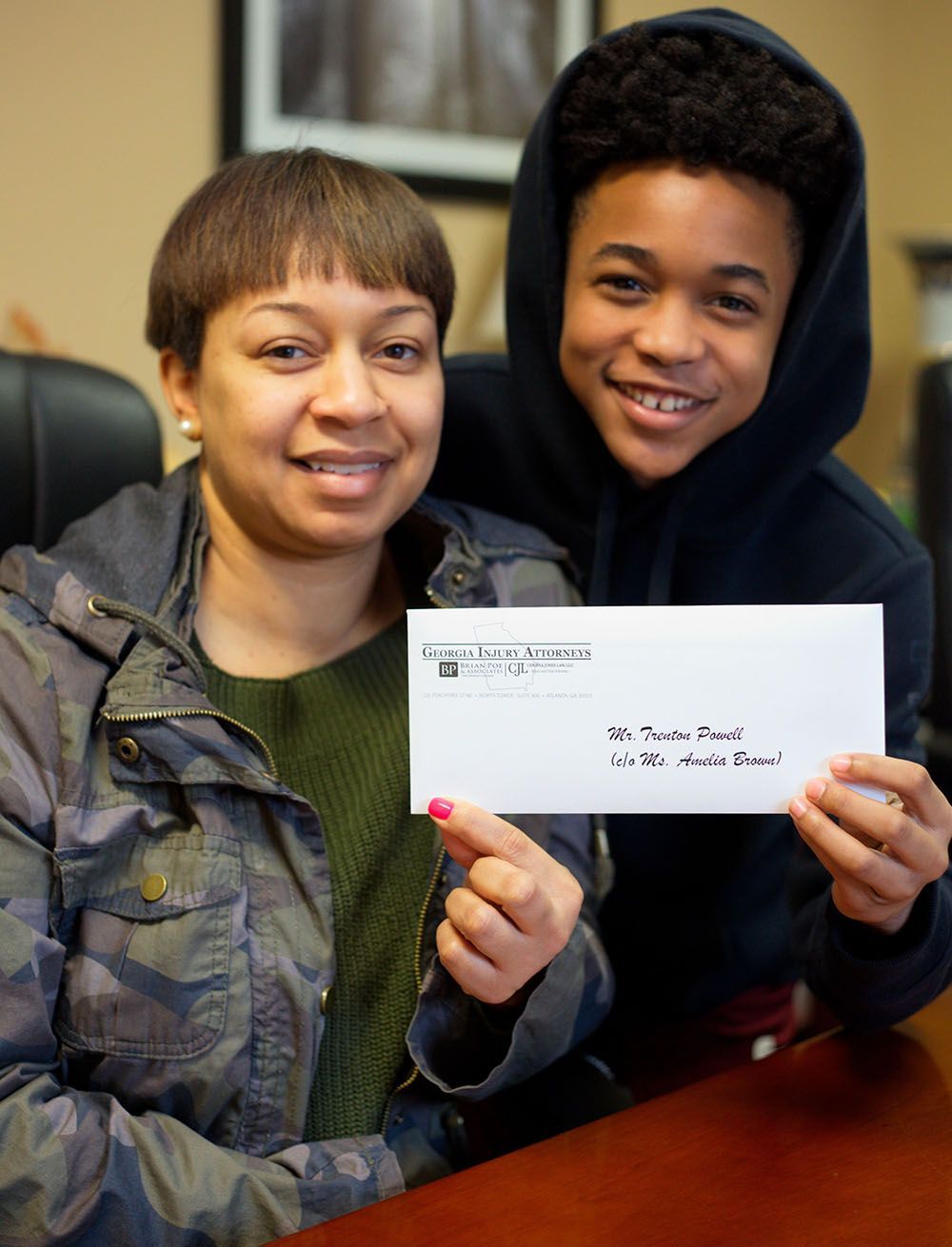 A woman and a boy are holding a check