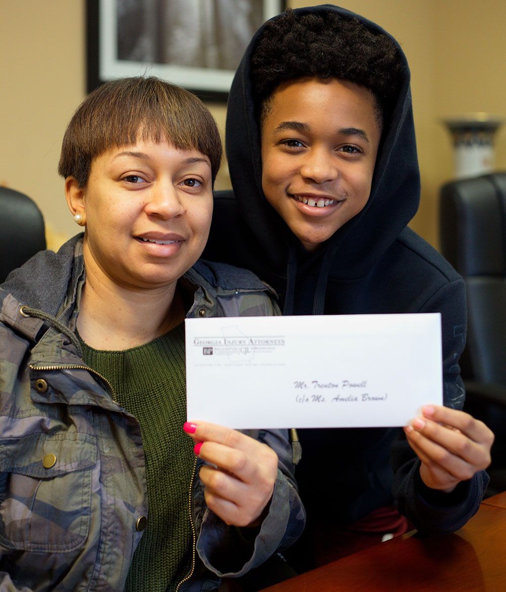 A happy woman and a boy are holding a check