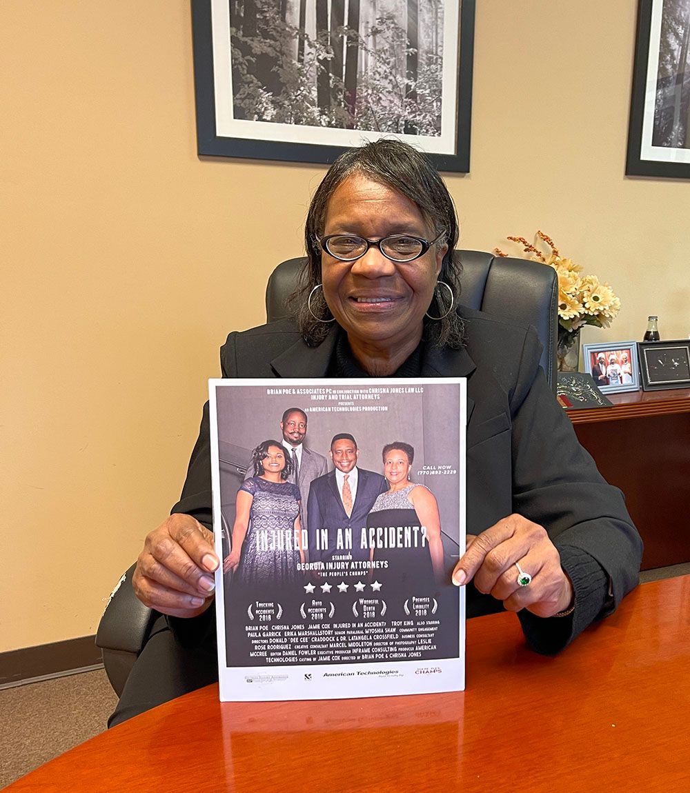A smiling woman is sitting at a table holding a flyer