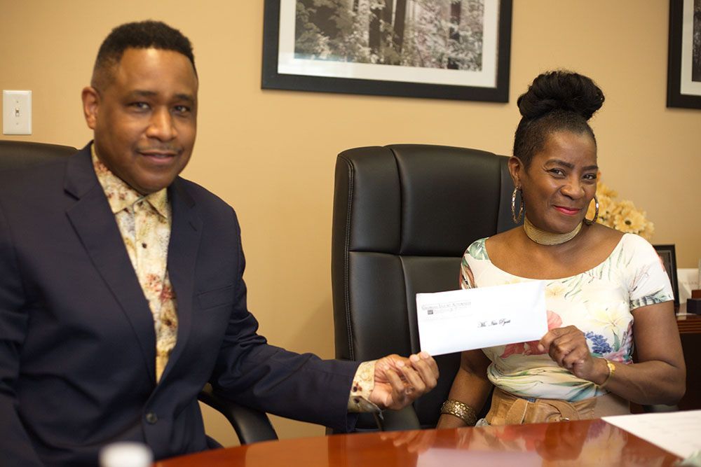 Brian D. Poe, Esq. giving a check to a cheerful client
