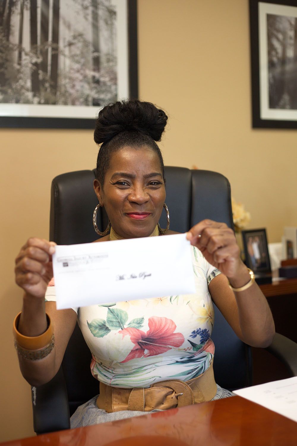 A woman is sitting at a desk holding a check