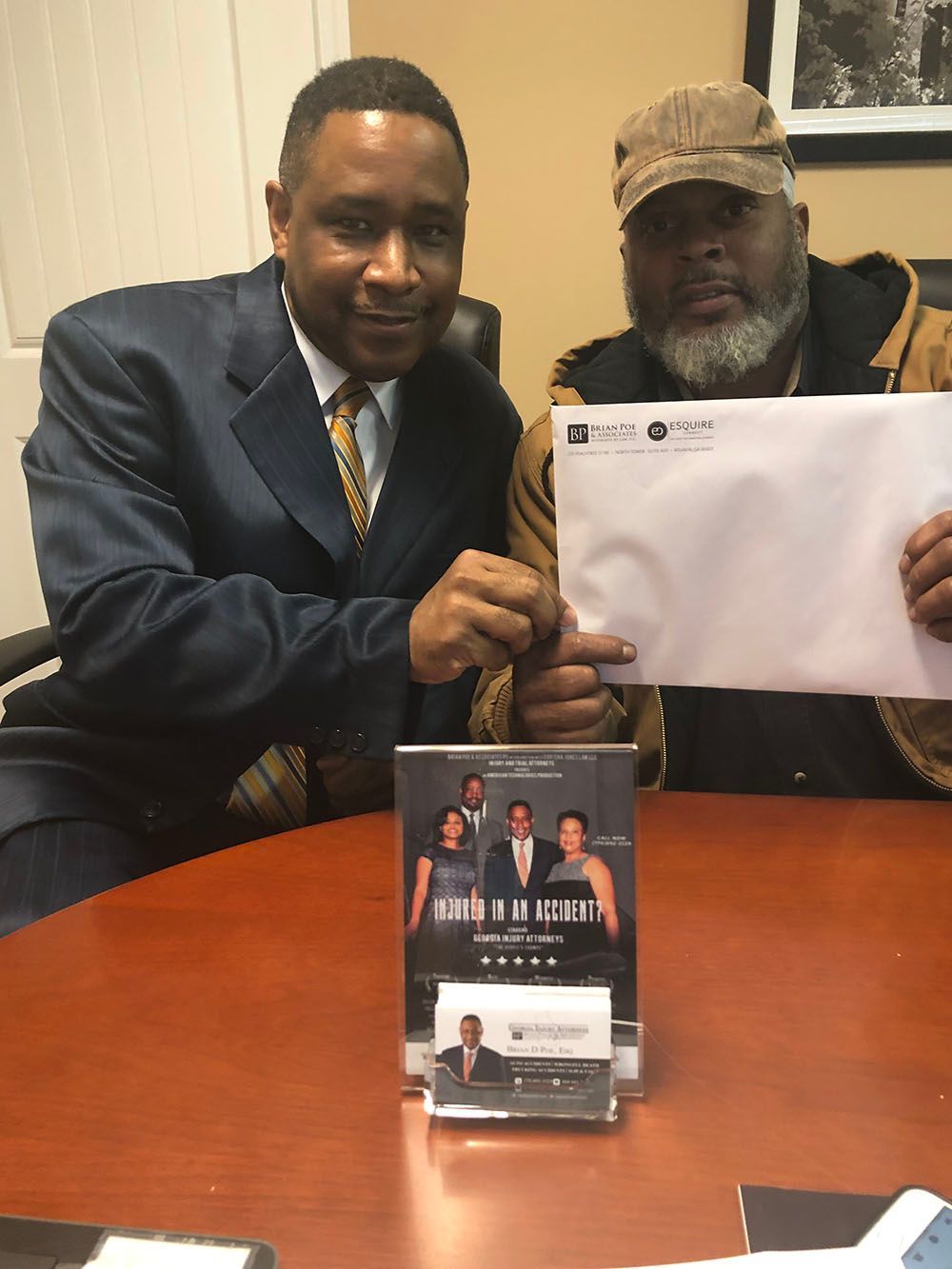 Brian D. Poe, Esq. with a happy client holding an envelope