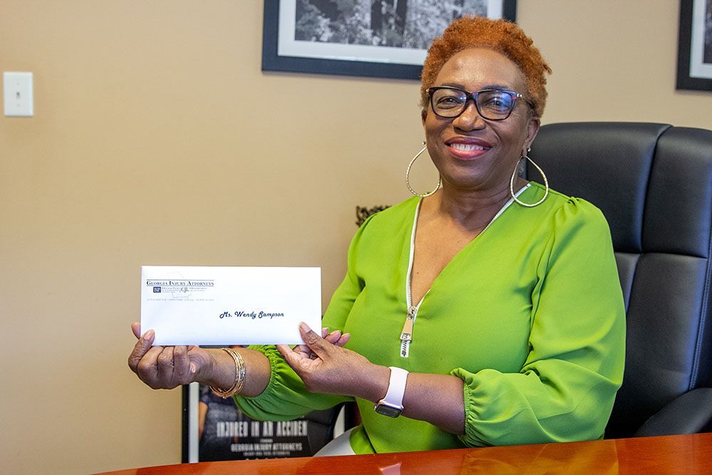 A woman in a green dress is sitting at a desk holding a check