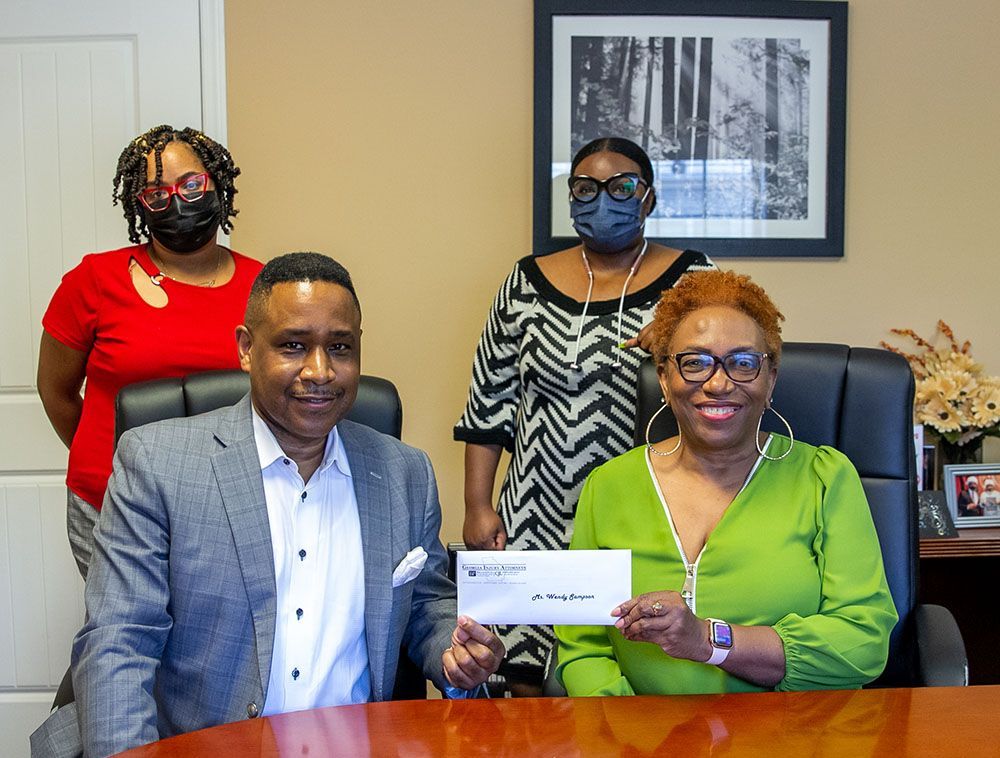 Brian D. Poe, Esq. and a cheerful female client are sitting at a table holding a check
