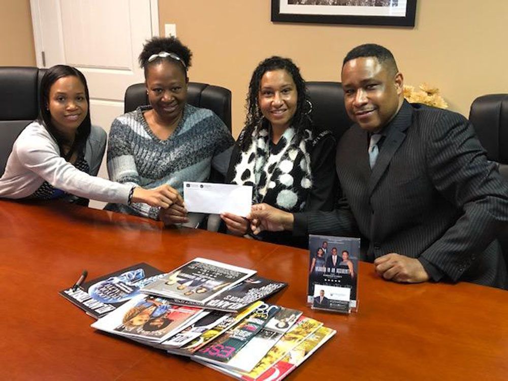 A group of people are sitting around a table holding a check