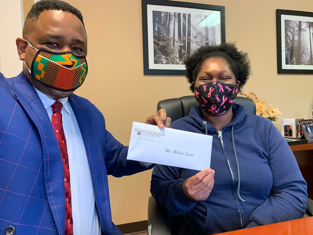 Brian D. Poe, Esq. is holding an envelope next to a woman wearing a mask