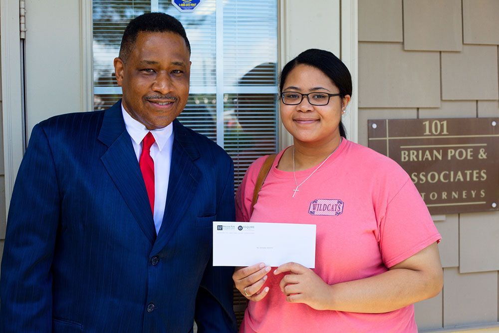 Brian D. Poe, Esq. handing a check to a happy client