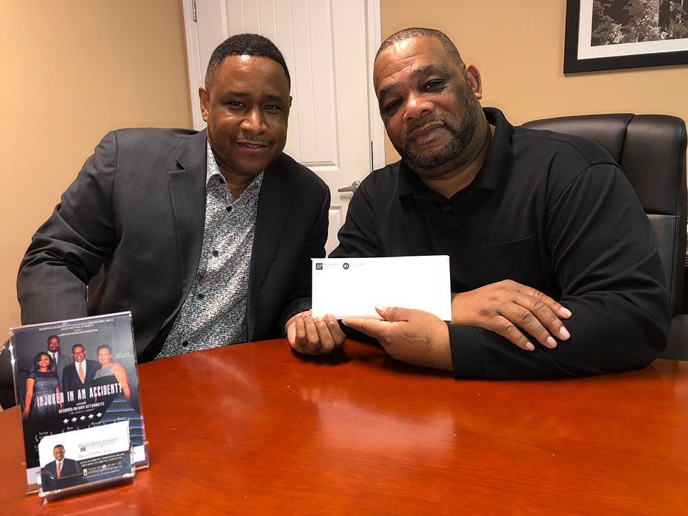 An attorney and a client are sitting at a table holding a check
