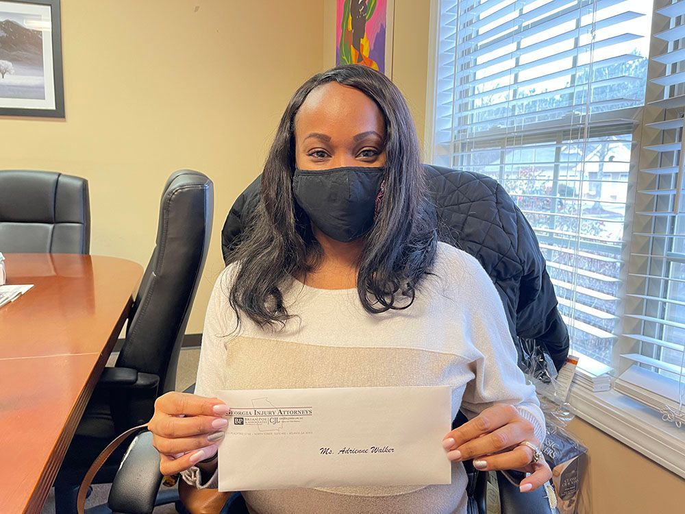 A woman wearing a mask is sitting in a chair holding a check