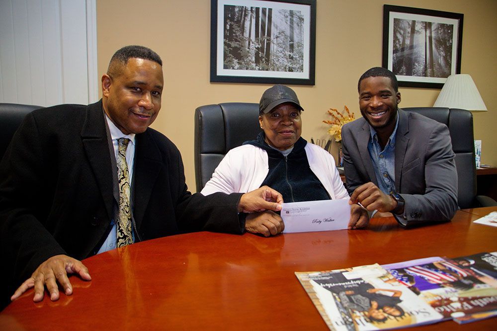 Georgia Injury Attorneys and a woman are sitting at a table holding a check
