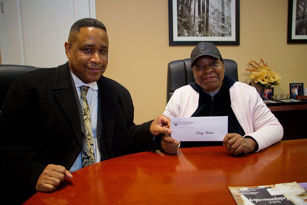 Brian D. Poe, Esq. and a woman are sitting at a table holding a check