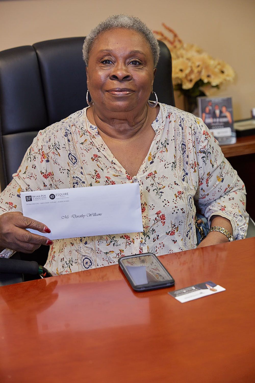 A woman is sitting at a desk holding a check