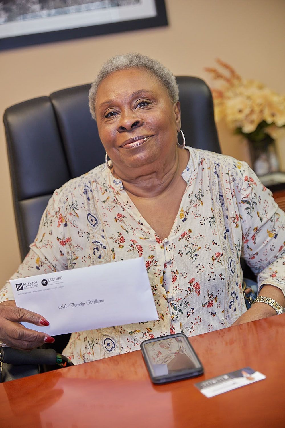 A happy client is sitting at a desk holding a check