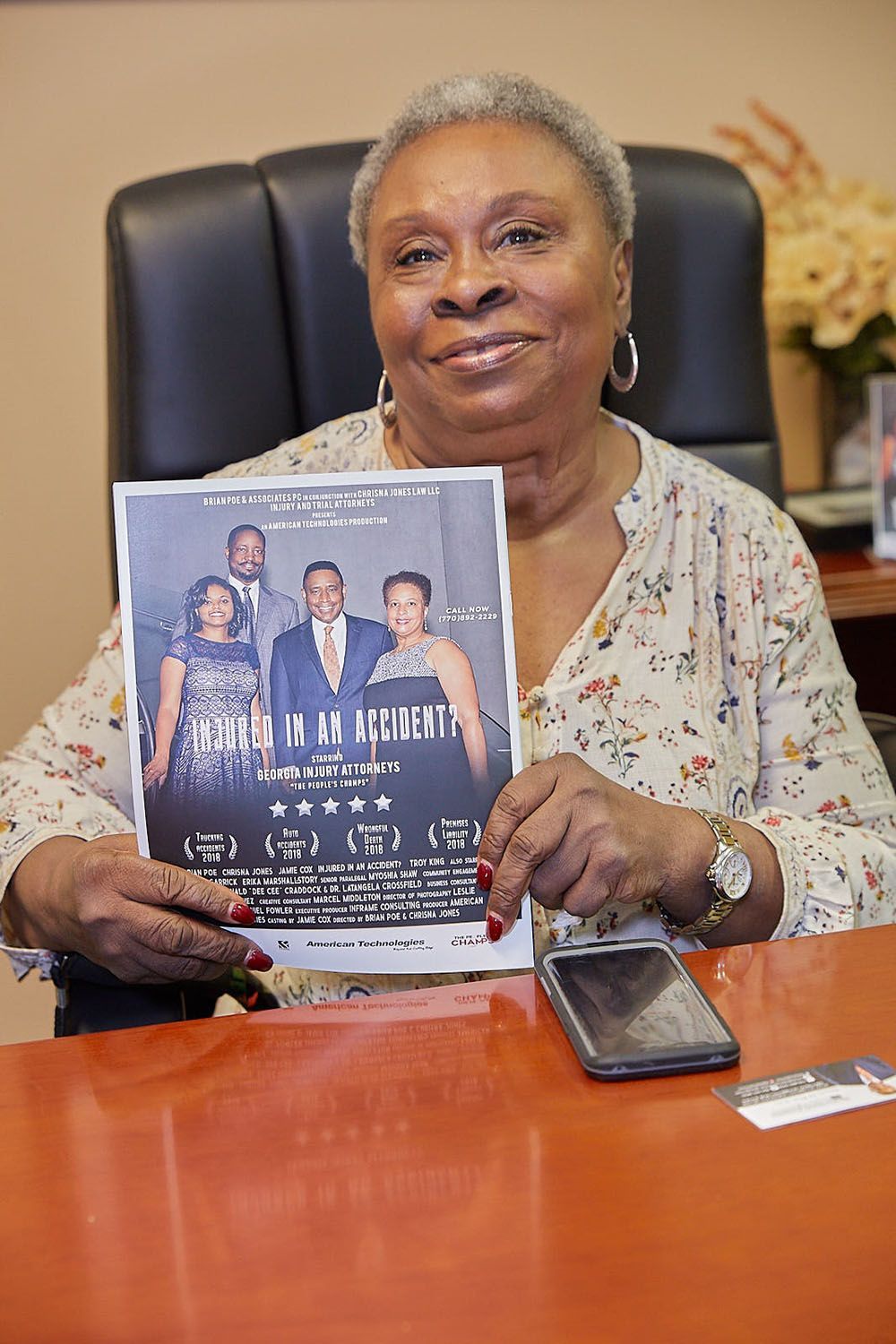 A woman is sitting at a desk holding a flyer