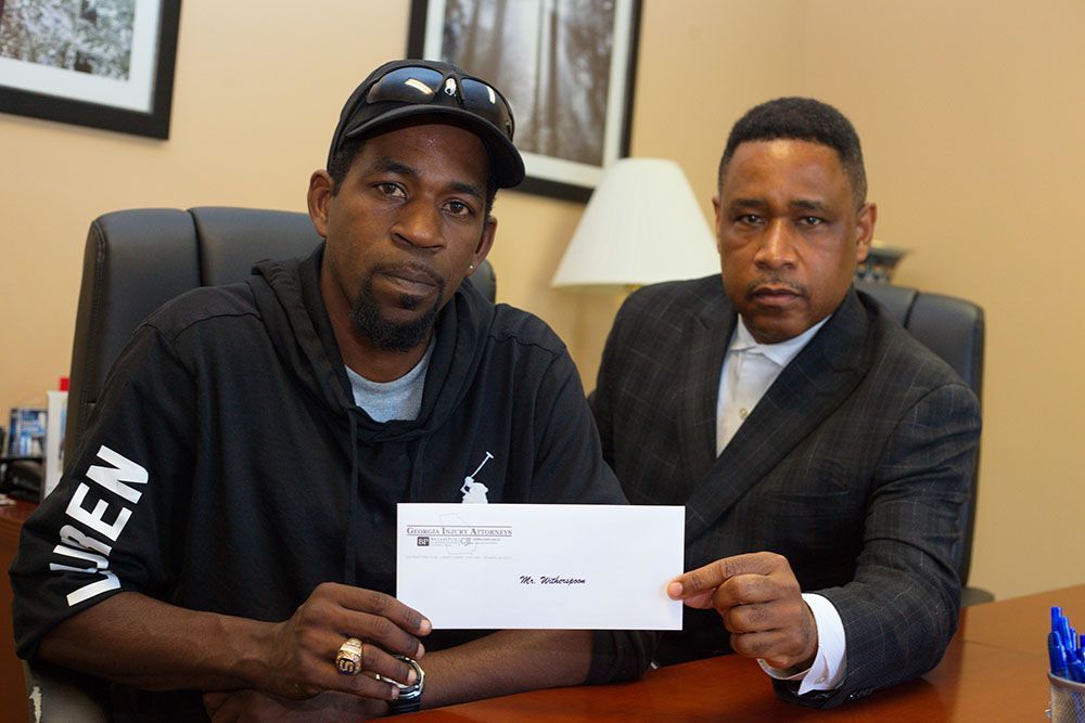 Handing a check to a man in a black hoodie