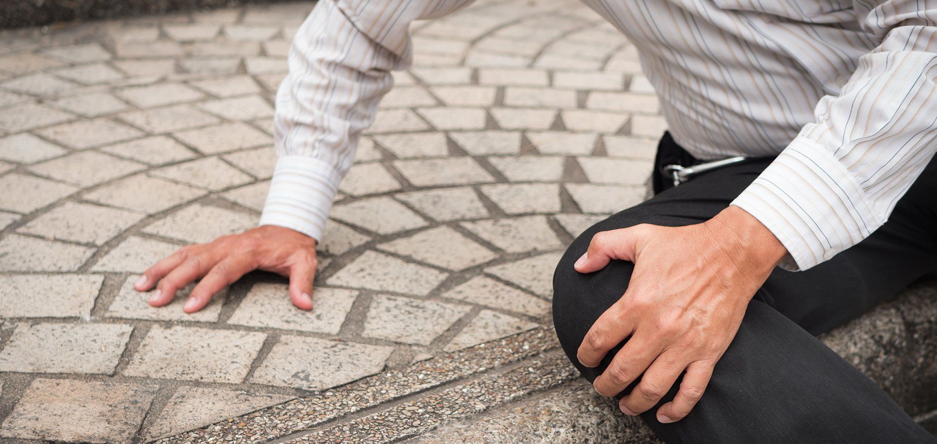 Closeup view a fallen man on the sidewalk holding his knee