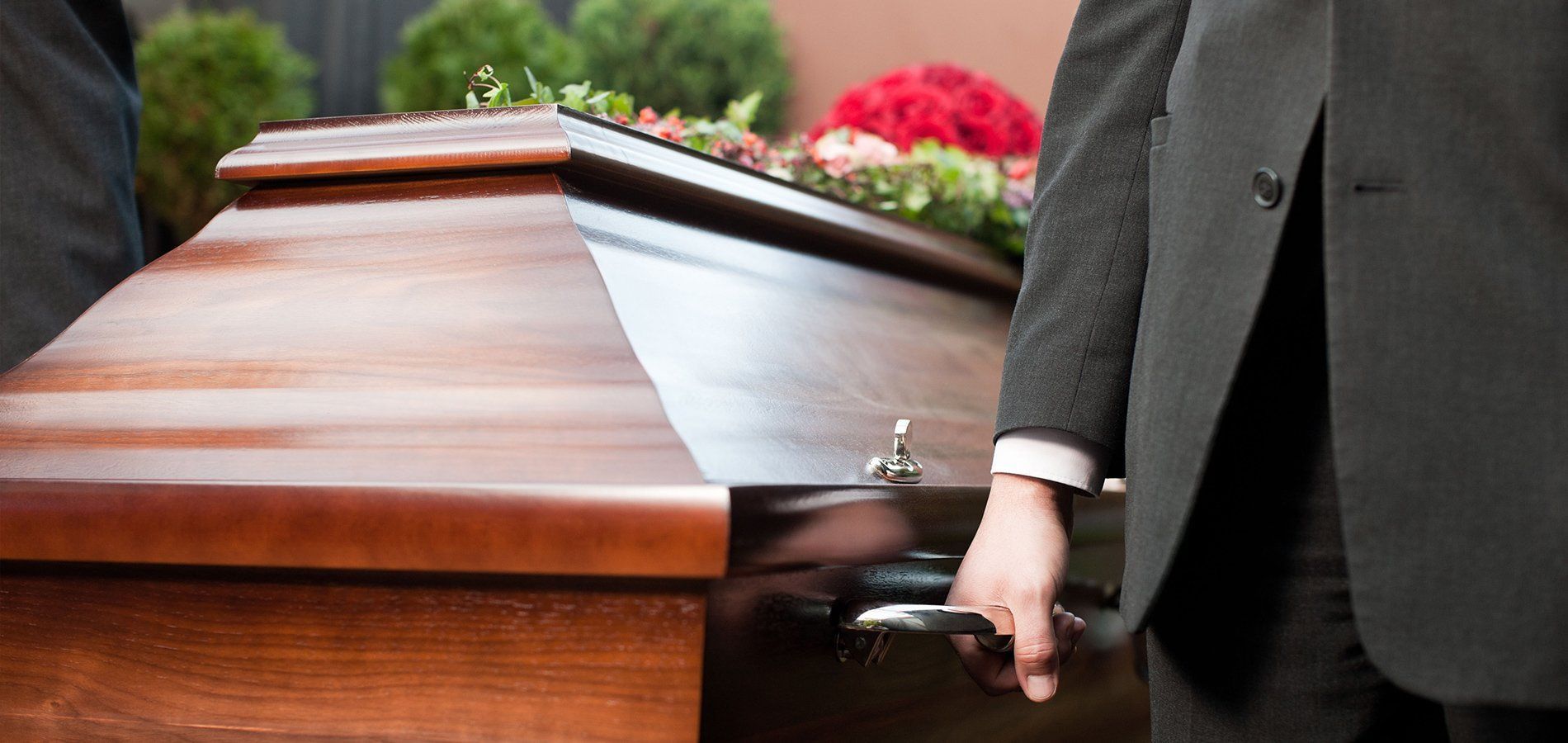 Closeup view of a pall bearer's hand holding a casket at a funeral