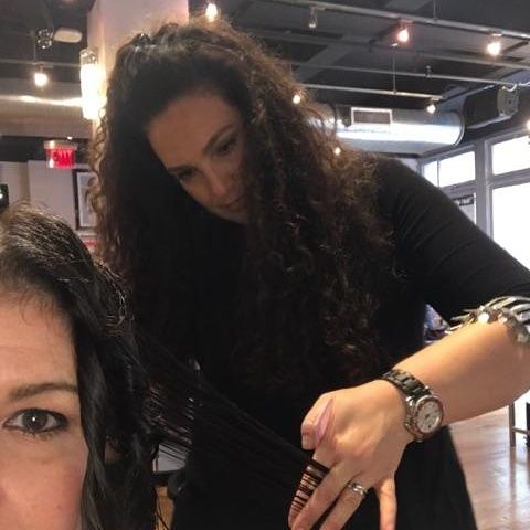 A woman wearing a watch is brushing another woman 's hair