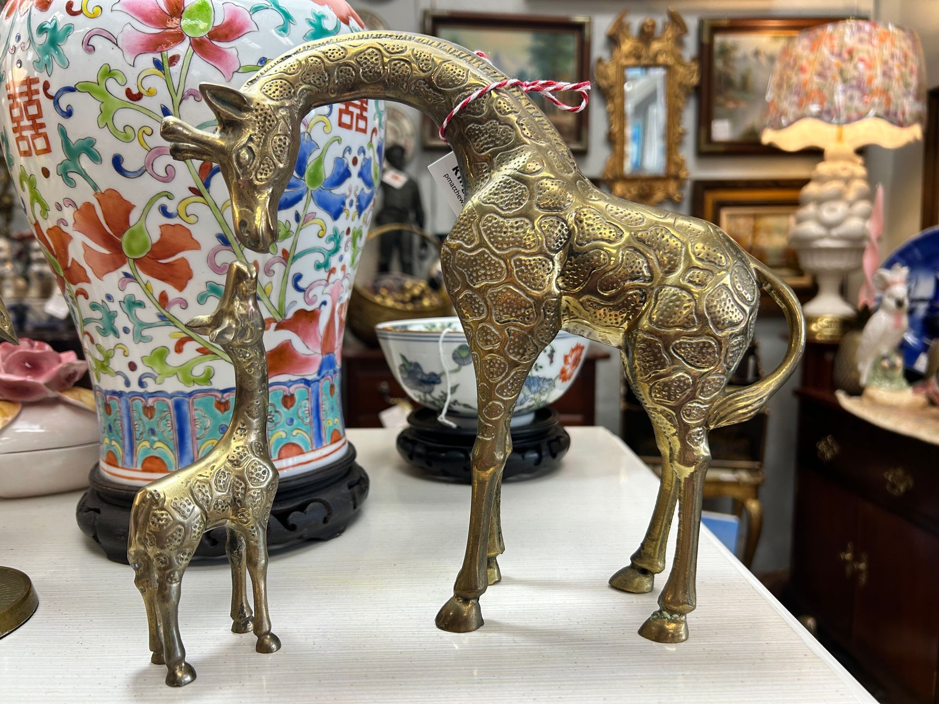 Two ornate, etched brass giraffe figurines, one large and one small, were displayed on a table in a shop.