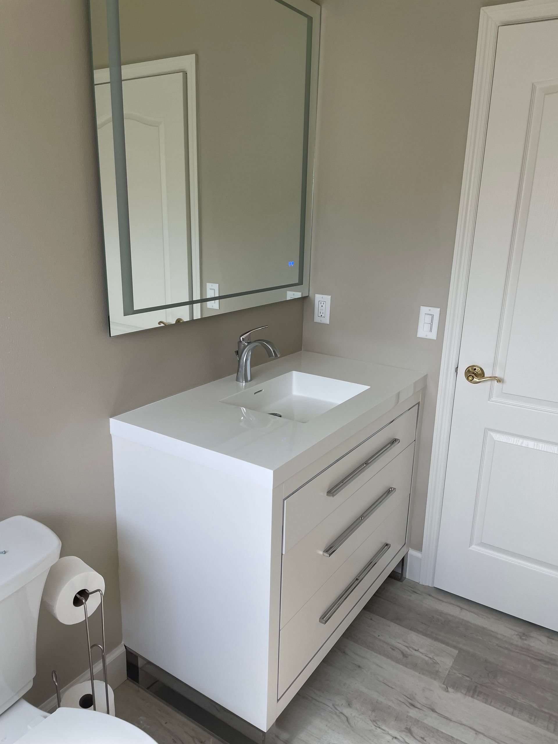 White bathroom vanity with three drawers, square sink, chrome faucet, and rectangular mirror.