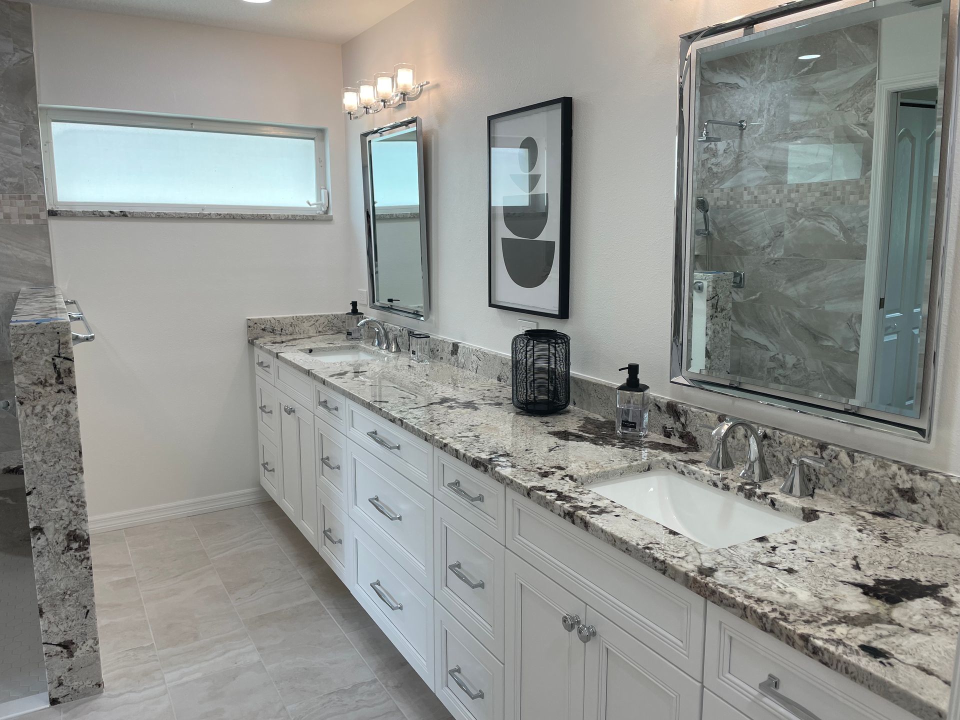 White bathroom with double vanity, granite countertop, and large mirrors.