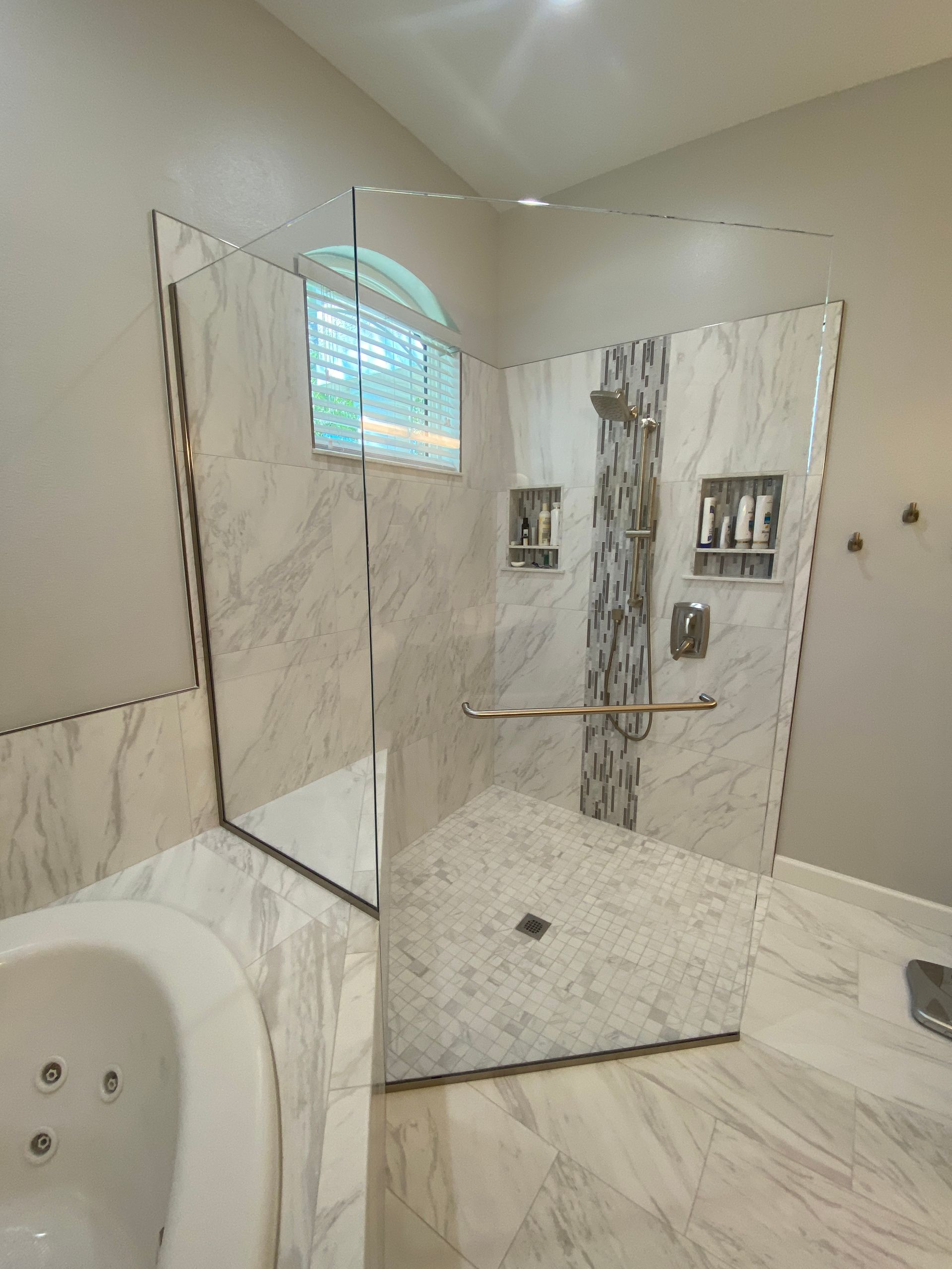 Modern bathroom with marble tile and glass shower enclosure.